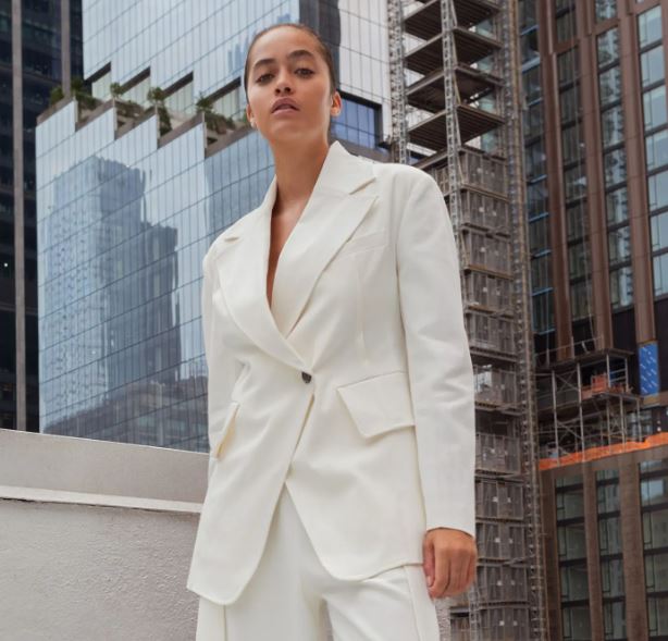 runway model standing in front of skyscrapers in a white suit looking fiercely into the camera
