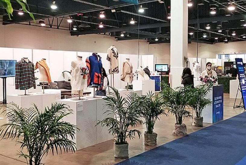 tradeshow booth with a selection of fashion items and small palm trees as decoration
